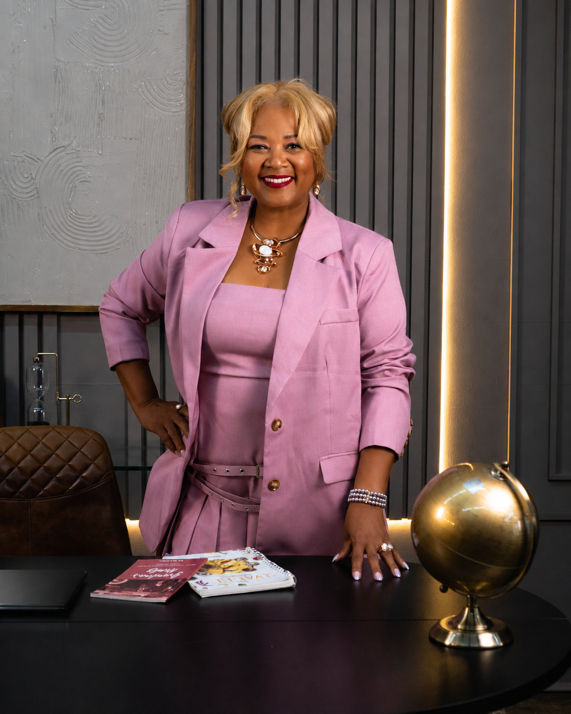 Kitura Smith standing at an executive desk with a brass globe and her books